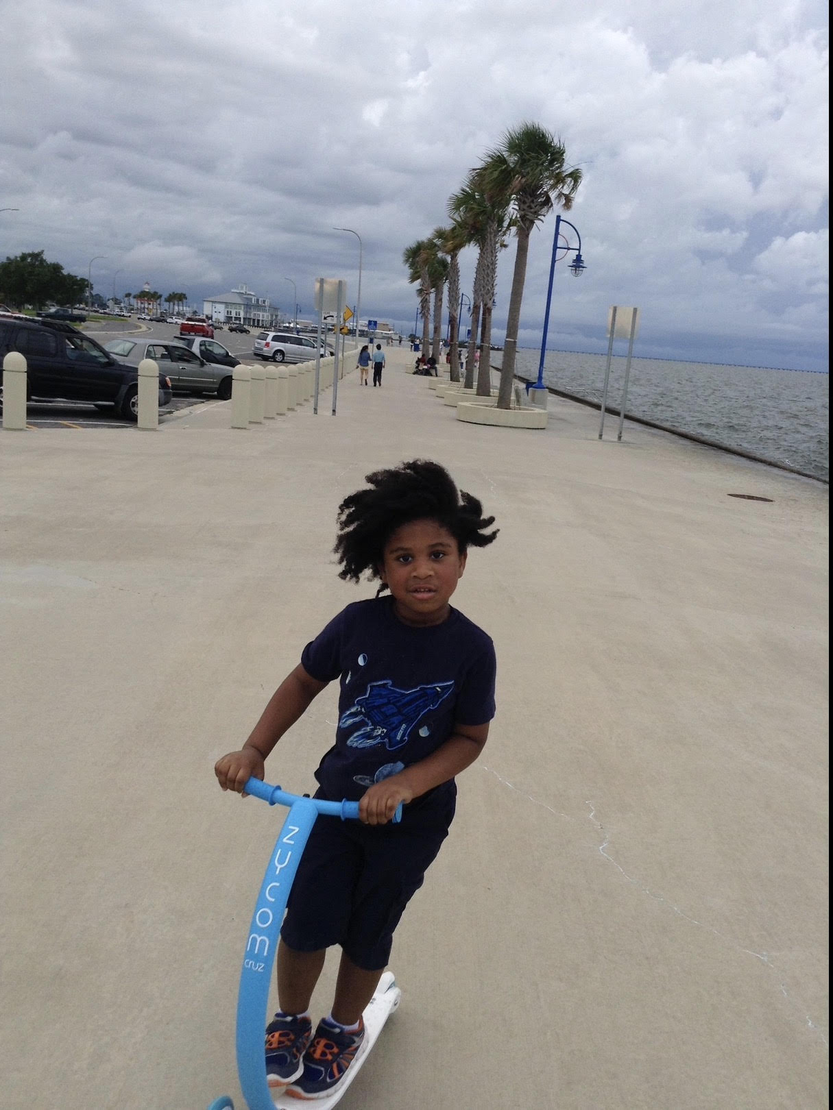 A Black child riding a scooter outdoors